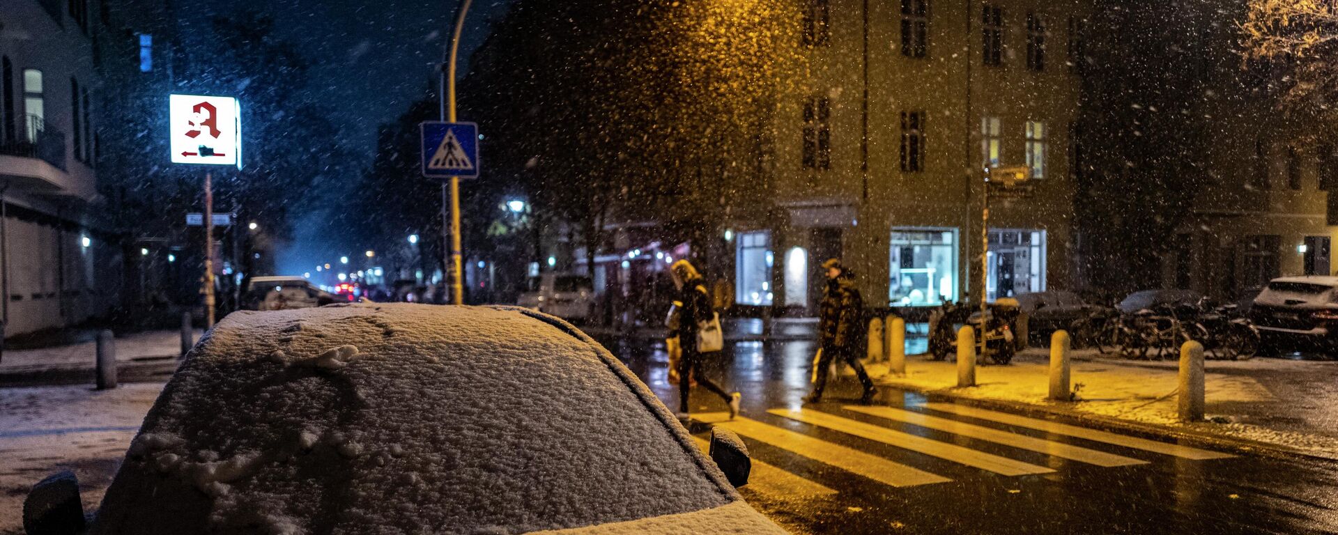 Припаркованная машина покрыта снегом, когда люди идут по пешеходному переходу во время раннего снегопада в Берлине. Архивное фото - Sputnik Кыргызстан, 1920, 26.11.2022