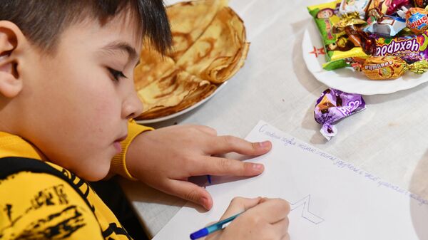 Мальчик сидит за столом с конфетами. Архивное фото - Sputnik Кыргызстан