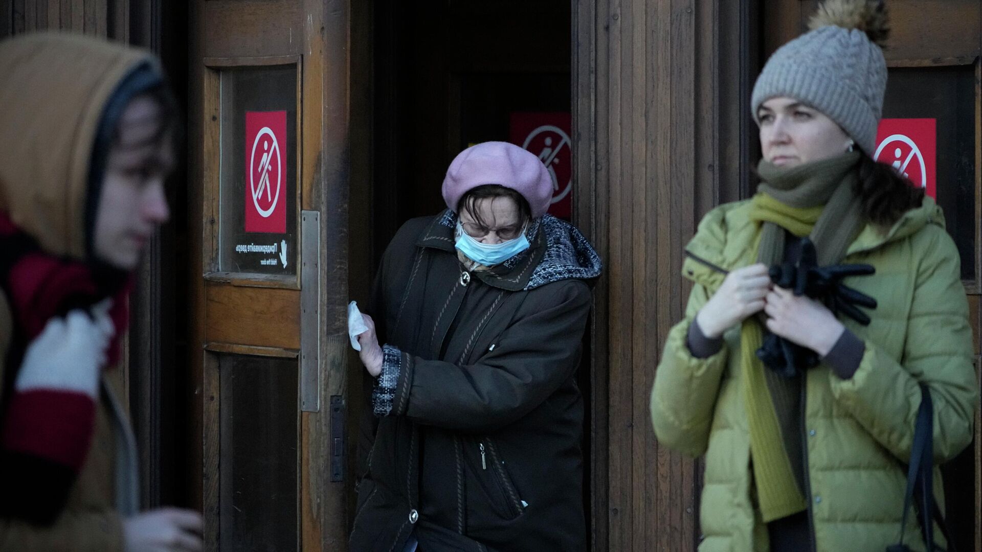 Женщина в маске для защиты от коронавируса толкает дверь медицинской салфеткой. Архивное фото - Sputnik Кыргызстан, 1920, 12.01.2023