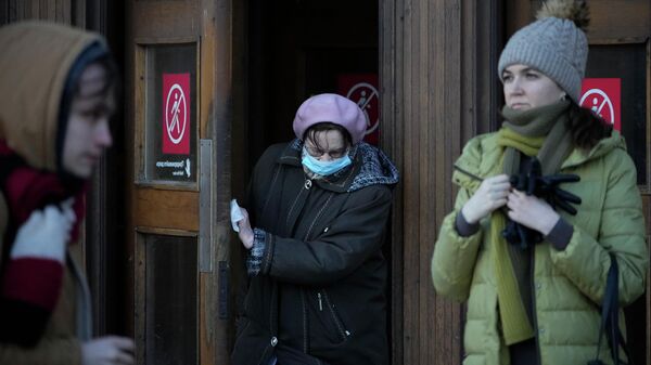 Женщина в маске для защиты от коронавируса толкает дверь медицинской салфеткой. Архивное фото - Sputnik Кыргызстан