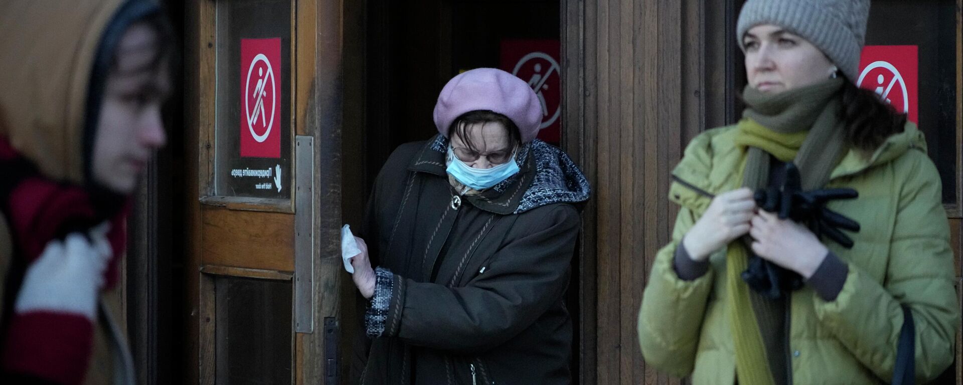 Женщина в маске для защиты от коронавируса толкает дверь медицинской салфеткой. Архивное фото - Sputnik Кыргызстан, 1920, 12.01.2023