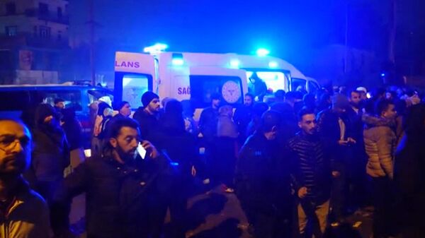 Люди рядом с машиной скорой помощи, пока спасатели ищут жертв землетрясения, которое произошло в Турции - Sputnik Кыргызстан