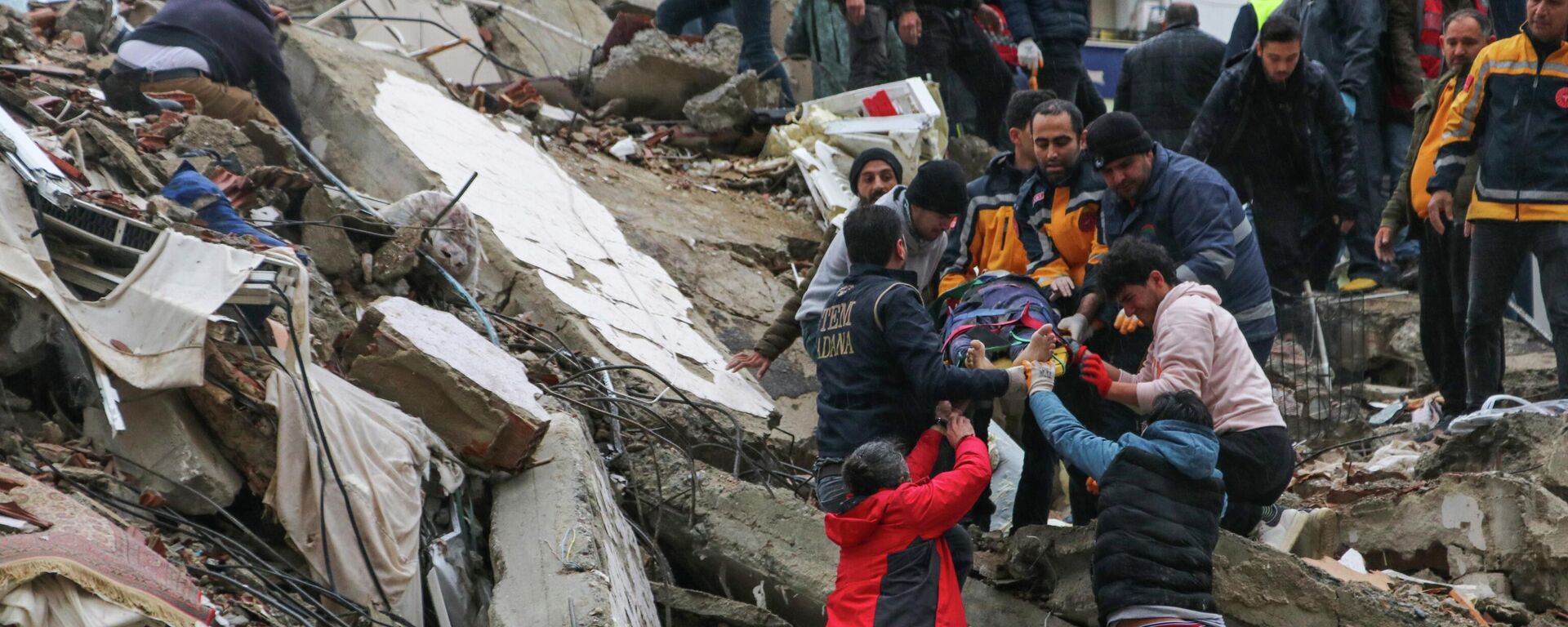 Люди и спасатели выносят пострадавшего из рухнувшего здания в Адане, Турция - Sputnik Кыргызстан, 1920, 06.02.2023