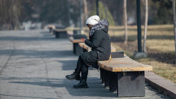 Бишкекте кыз телефон менен отургучта отуруп жатат. Архив - Sputnik Кыргызстан
