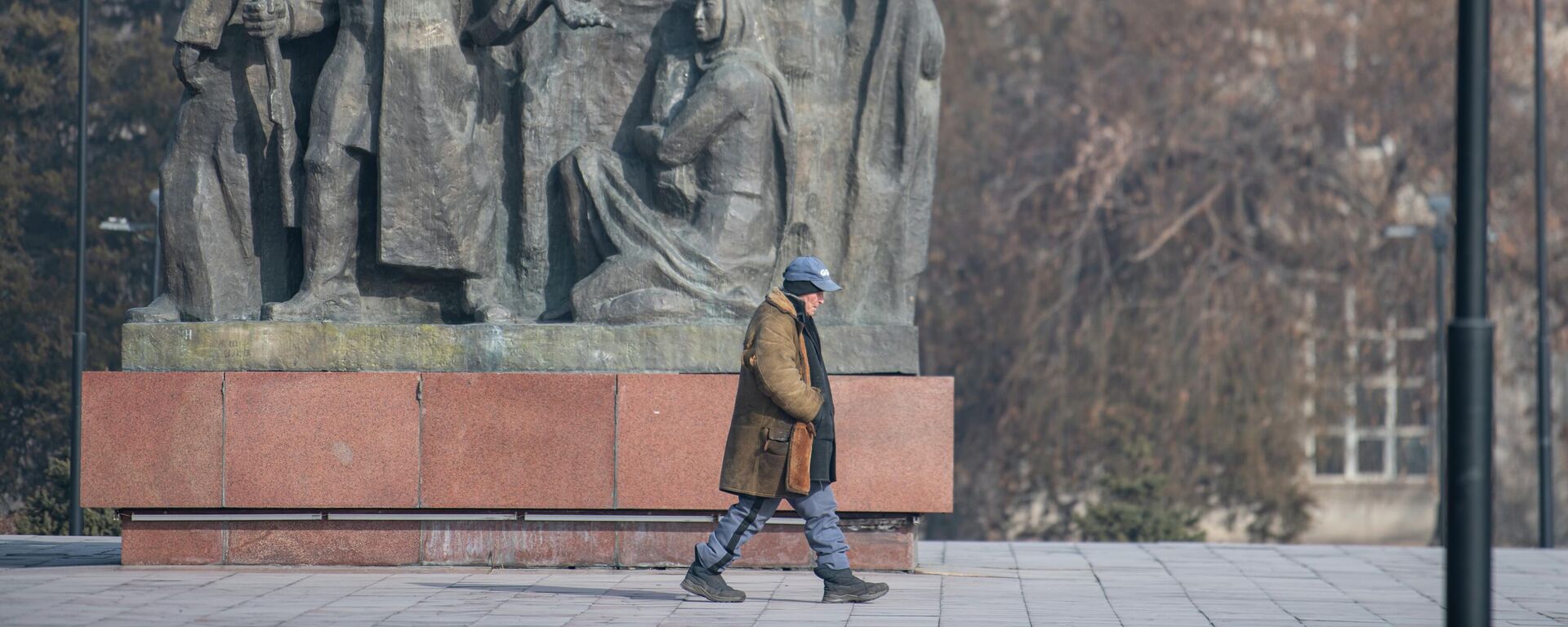 Пожилой мужчина проходит мимо памятника борцам революции в Бишкеке - Sputnik Кыргызстан, 1920, 16.02.2023