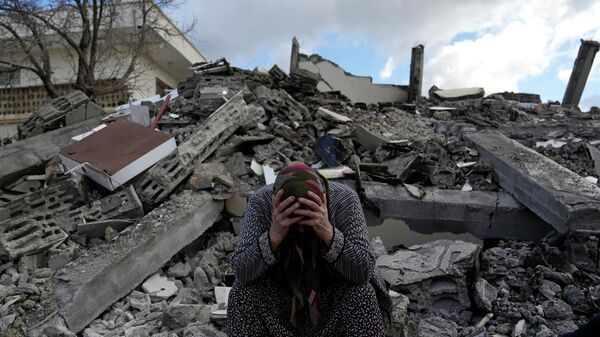 Женщина сидит на развалинах разрушенного во время землетрясения дома в городе Нурдаги, Турция - Sputnik Кыргызстан