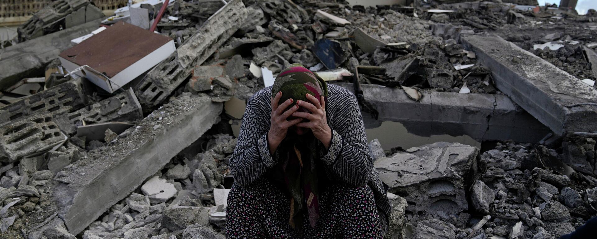 Женщина сидит на развалинах разрушенного во время землетрясения дома в городе Нурдаги, Турция - Sputnik Кыргызстан, 1920, 09.02.2023