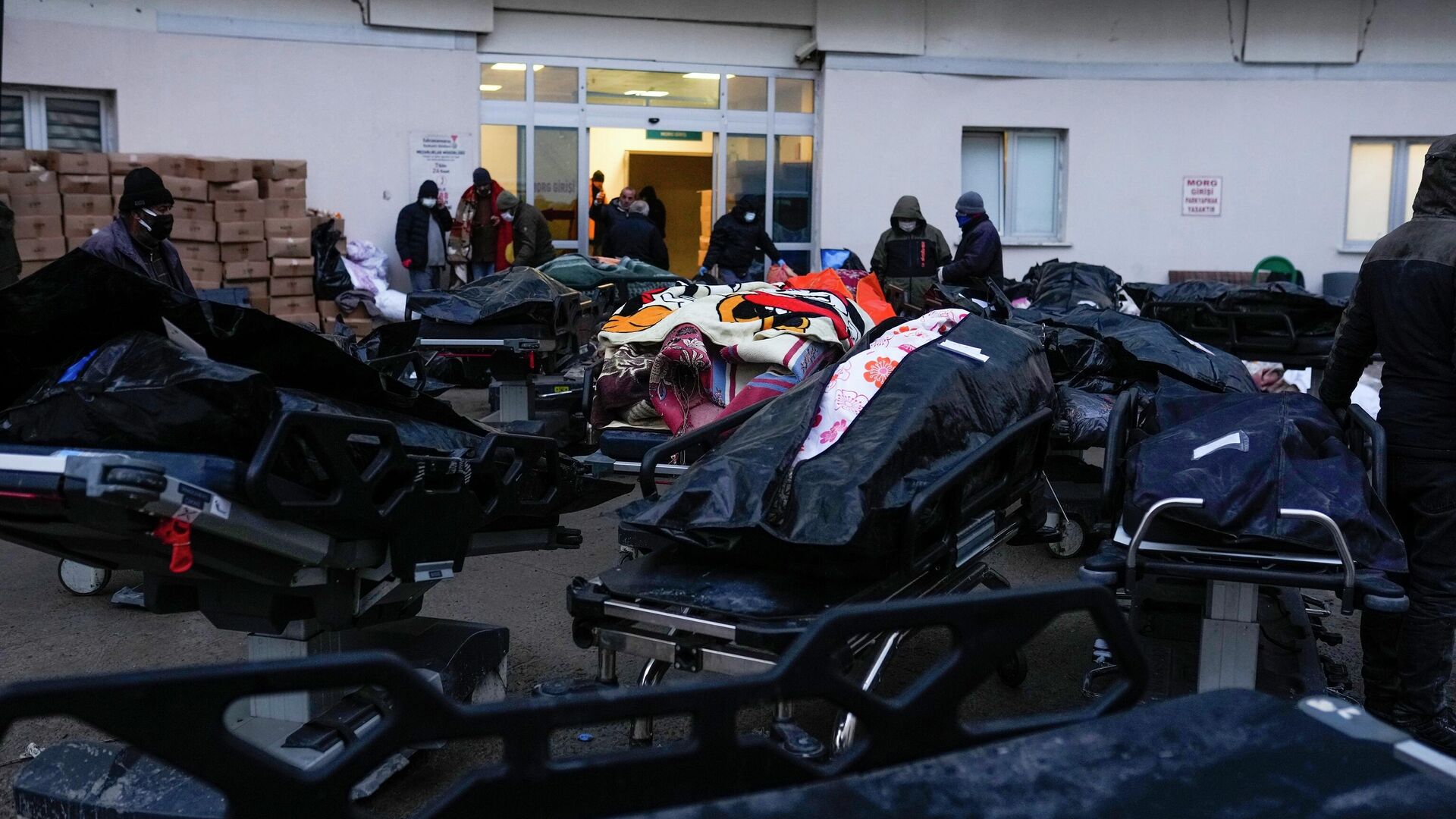 Люди стоят рядом с телами жертв землетрясения в больнице в Эльбистане, юго-восточная Турция - Sputnik Кыргызстан, 1920, 10.02.2023