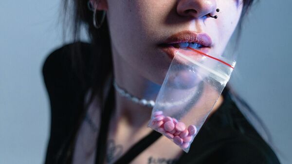Девушка с пакетиком таблеток во рту. Иллюстративное фото - Sputnik Кыргызстан