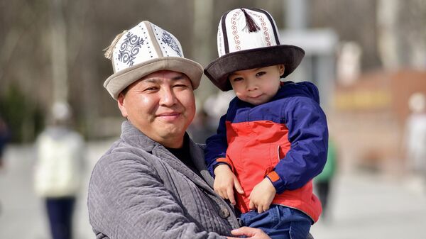 Мужчина с сыном на праздновании Дня ак калпака на площади Ала-Тоо в Бишкеке - Sputnik Кыргызстан