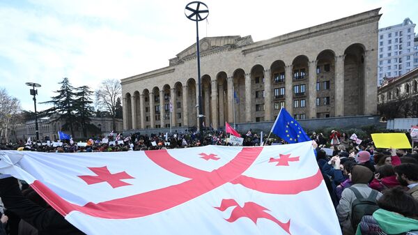 Люди размахивают гигантским грузинским флагом во время демонстрации у здания парламента Грузии в Тбилиси - Sputnik Кыргызстан