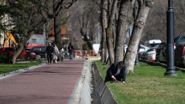 Мужчина чистит коврик автомобиля у арыка в Бишкеке. 23 марта 2023 года - Sputnik Кыргызстан
