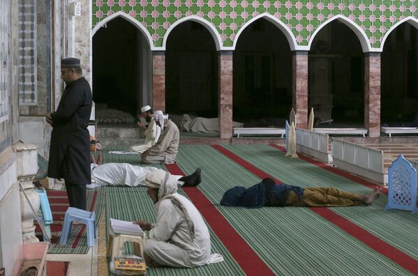 Одни мусульмане совершают полуденную молитву, а другие отдыхают в мечети в первый день священного месяца Рамадан в Пешаваре (Пакистан) - Sputnik Кыргызстан