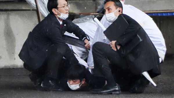 Япониянын премьер-министри Фумио Кисида сүйлөп жаткан жерде жардыруу болгондон кийин шектүүнү кармап жаткан полиция кызматкерлери - Sputnik Кыргызстан