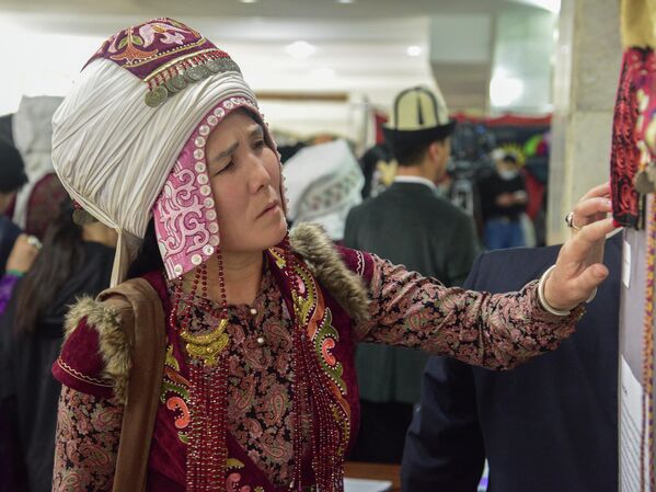 Женщина в традиционной одежде рассматривает узоры на вышивке - Sputnik Кыргызстан