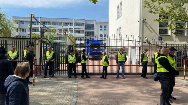 Представители мэрии в сопровождении полиции стоят возле ворот школы при российском посольстве в Варшаве - Sputnik Кыргызстан