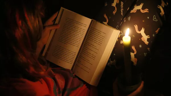 Ребенок читает книгу при свечах во время отключения электричества. Архивное фото - Sputnik Кыргызстан