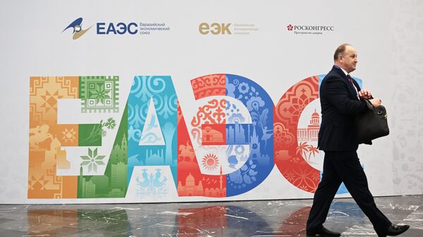Участник проходит рядом со стендом с символикой Евразийского экономического форума в Москве - Sputnik Кыргызстан