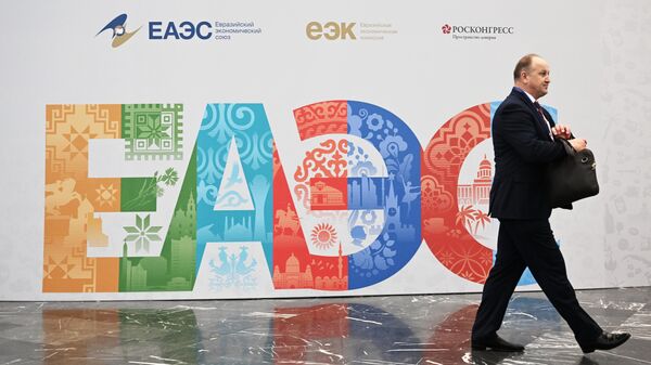 Участник форума ЕАЭС проходит рядом со стендом с символикой организации. Архивное фото - Sputnik Кыргызстан