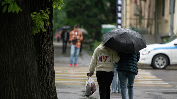 Женщины укрываются зонтом от дождя в Бишкеке. Архивное фото  - Sputnik Кыргызстан