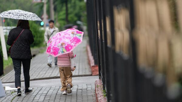 Женщина с ребенком во время дождливой погоды в Бишкеке - Sputnik Кыргызстан
