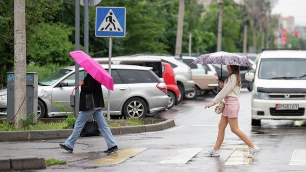 Пешеходы с зонтами переходят дорогу во время дождя в Бишкеке. Архивное фото - Sputnik Кыргызстан