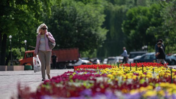 Женщина идет вдоль цветочной клумбы  в Бишкеке. Архивное фото - Sputnik Кыргызстан