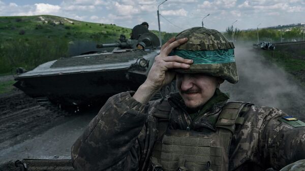 Украинский солдат держит каску на БТР в Бахмуте - Sputnik Кыргызстан