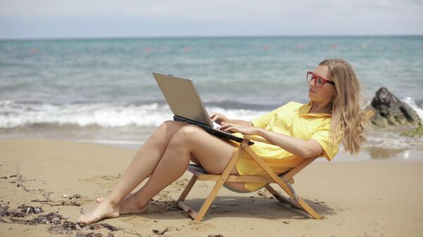 Девушка работает за ноутбуком на пляже. Иллюстративное фото - Sputnik Кыргызстан