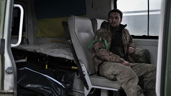Раненый украинский солдат сидит рядом с с завернутым телом в машине медицинской эвакуации на дороге недалеко от Бахмута. Архивное фото - Sputnik Кыргызстан
