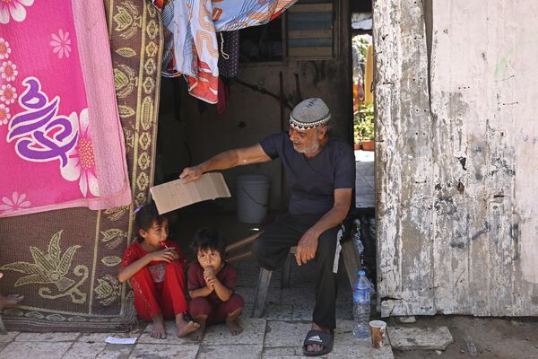 Мужчина машет куском картона, чтобы помочь детям охладиться (Палестина) - Sputnik Кыргызстан