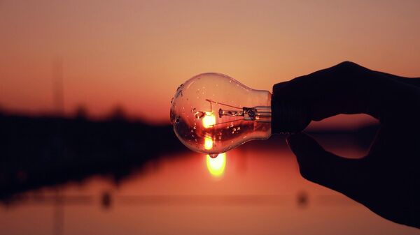 Человек держит лампочку на закате. Иллюстративное фото - Sputnik Кыргызстан