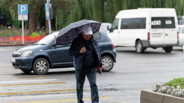 Мужчина под зонтом во время дождя переходит дорогу в Бишкеке - Sputnik Кыргызстан