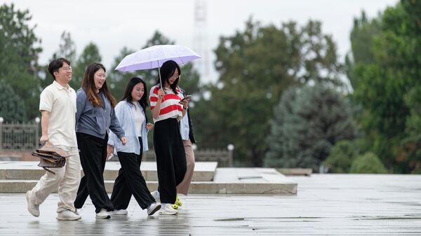 Молодые люди идут по площади Ала-Тоо во время дождя в Бишкеке. Архивное фото - Sputnik Кыргызстан