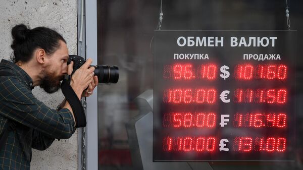 Мужчина фотографирует электронное табло у пункта обмена валют в Москве - Sputnik Кыргызстан
