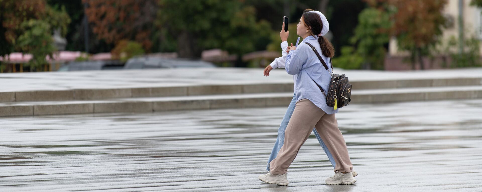 Девушки идут по площади Ала-Тоо в Бишкек, во время дождливой погоды  - Sputnik Кыргызстан, 1920, 07.09.2023