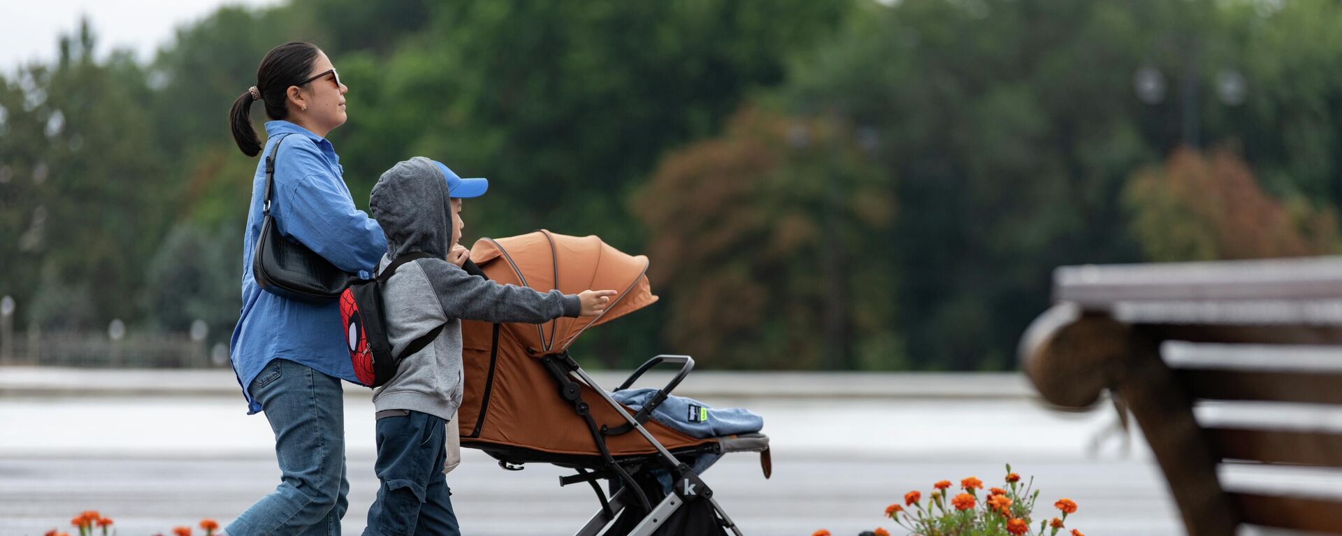 Женщина с ребенком идет по площади Ала-Тоо во время дождливой погоды в Бишкеке. 28 августа 2023 года - Sputnik Кыргызстан, 1920, 06.09.2023