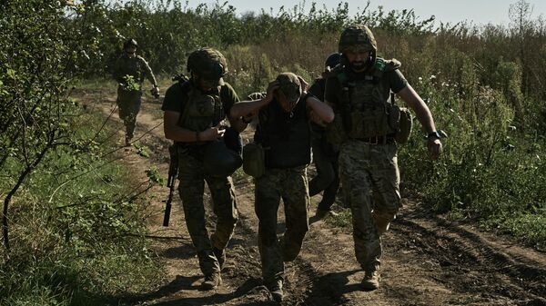 Украинские военнослужащие помогают эвакуировать раненого солдата на передовой под Бахмутом - Sputnik Кыргызстан