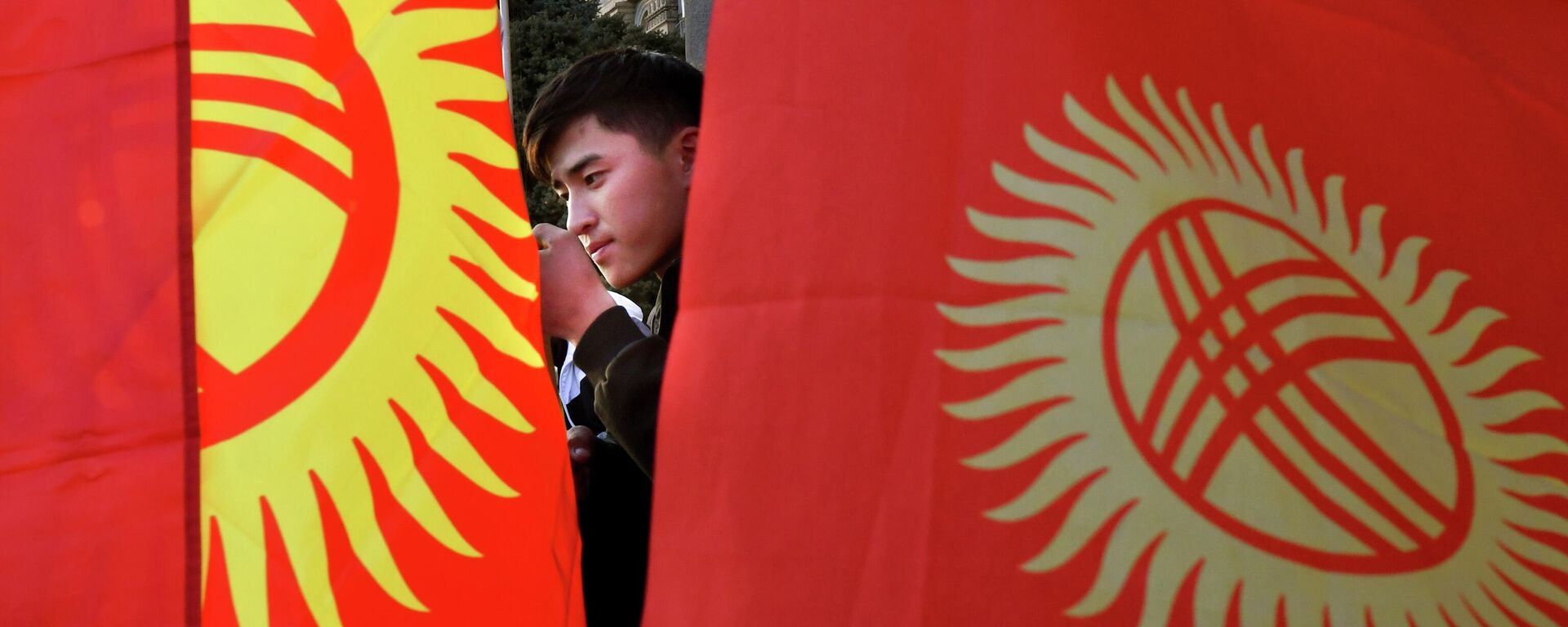 Молодой человек на фоне флагов Кыргызстана. Архивное фото - Sputnik Кыргызстан, 1920, 23.09.2023