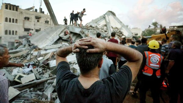 Мужчина реагирует, наблюдая, как спасатели и мирные жители разбирают завалы дома, разрушенного после нападения Израиля на город Дейр-эль-Балах в центральной части сектора Газа. Архивное фото - Sputnik Кыргызстан