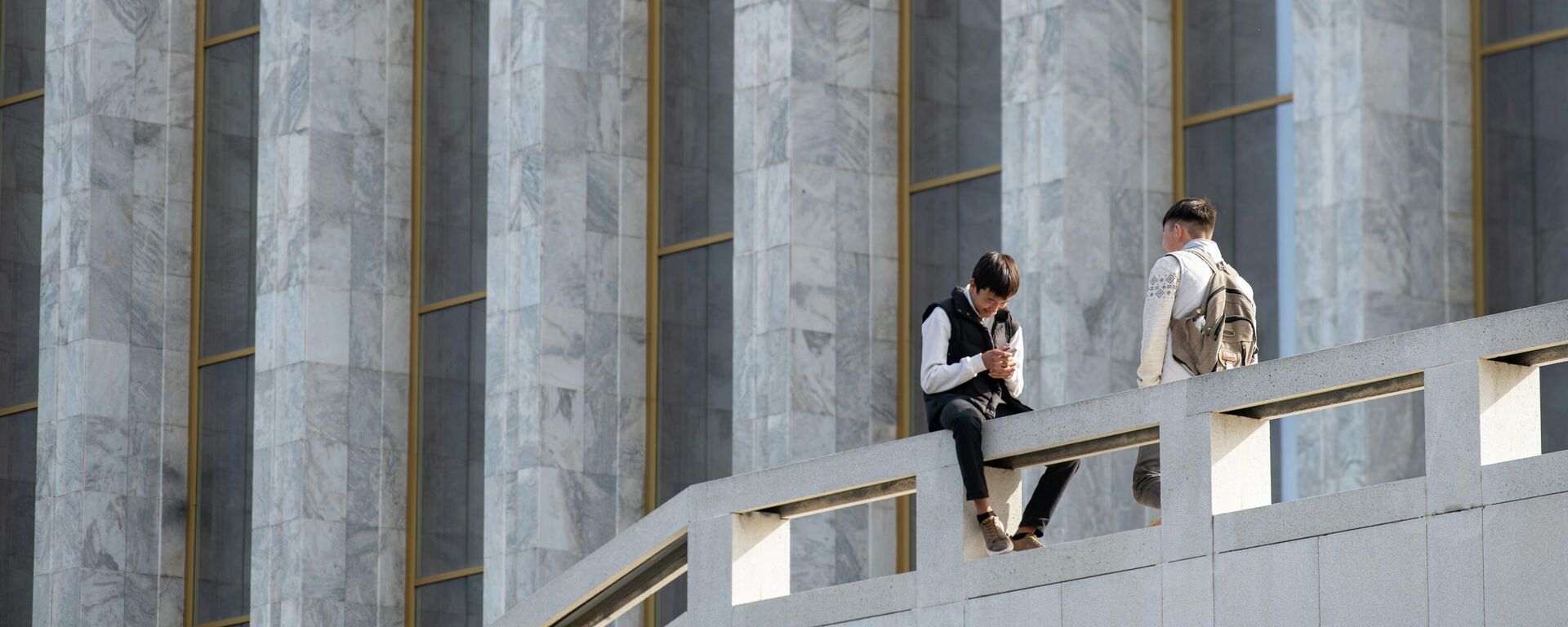 Молодые люди сидят у здания правительства в Бишкеке - Sputnik Кыргызстан, 1920, 04.08.2025