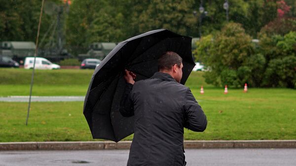 Мужчина идет под зонтом во время дождя - Sputnik Кыргызстан