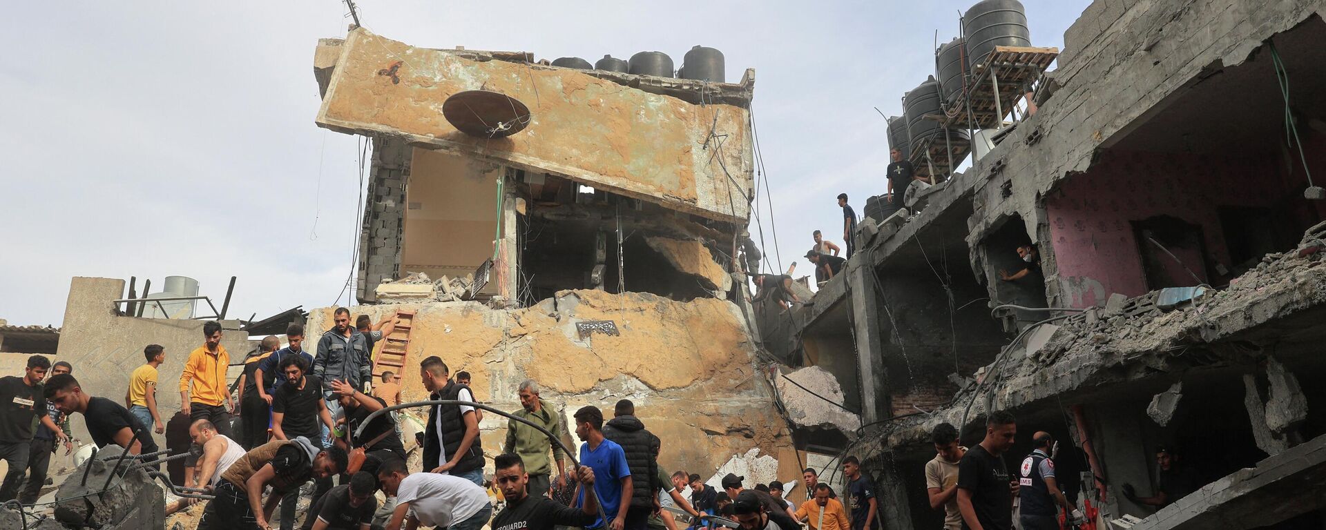 Люди ищут жертв среди обломков здания, пострадавшего от израильской бомбардировки, в Рафахе на юге сектора Газа - Sputnik Кыргызстан, 1920, 11.11.2023