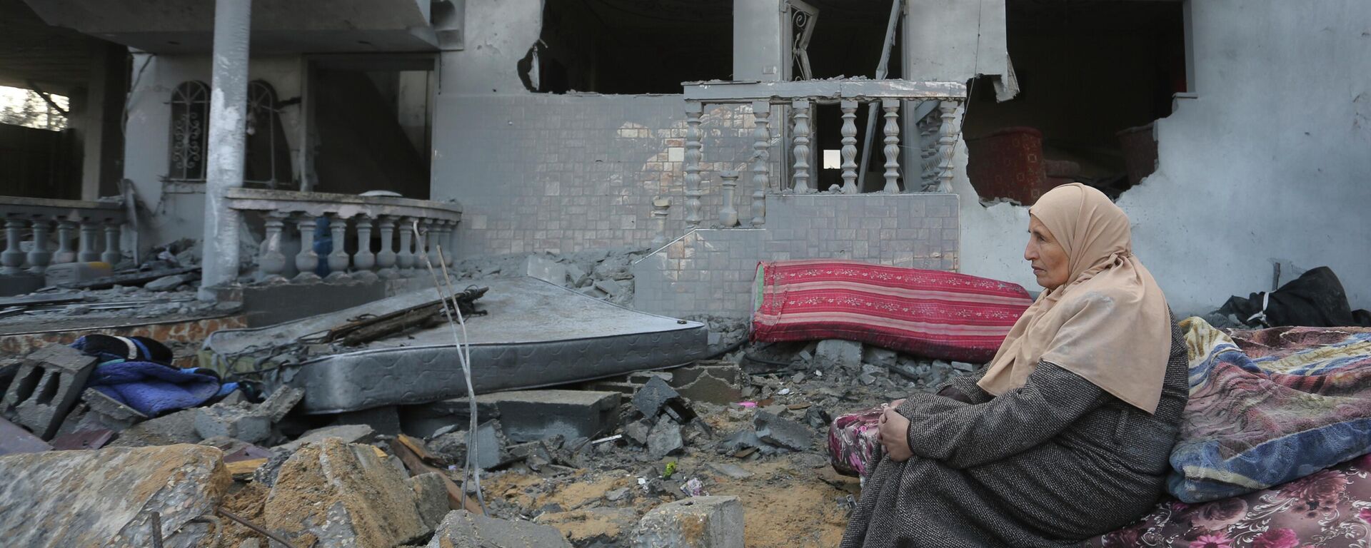 Палестинская женщина сидит возле домов, разрушенных в результате израильской бомбардировки сектора Газа - Sputnik Кыргызстан, 1920, 21.11.2023
