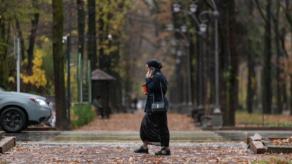 Девушка разговаривает по телефону в дождливый день в Бишкеке. Архивное фото - Sputnik Кыргызстан
