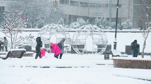 Люди во время снегопада на площади Ала-Тоо в Бишкеке - Sputnik Кыргызстан