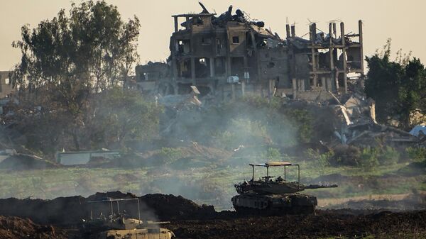 Израилдин танкалары Газа тилкесинин түндүгүндө талкаланган имараттын жанында турат - Sputnik Кыргызстан