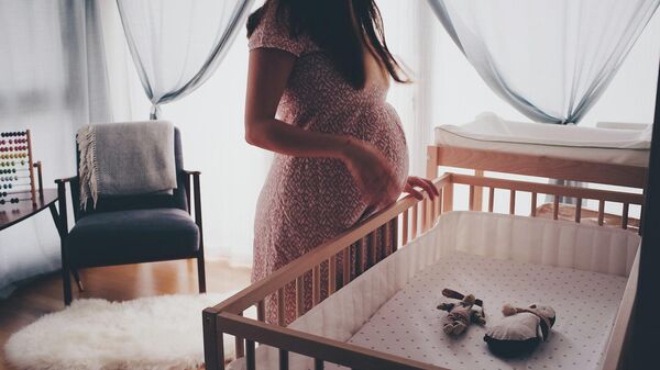 Женщина с беременностью стоит у детской кроватки. Иллюстративное фото - Sputnik Кыргызстан