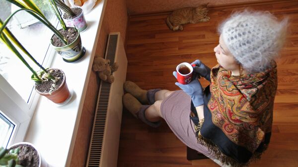 Женщина сидит в теплой одежде у батареи в квартире. Архивное фото  - Sputnik Кыргызстан