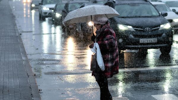 Пожилая женщина с зонтом переходит дорогу во время снегопада. Архивное фото  - Sputnik Кыргызстан